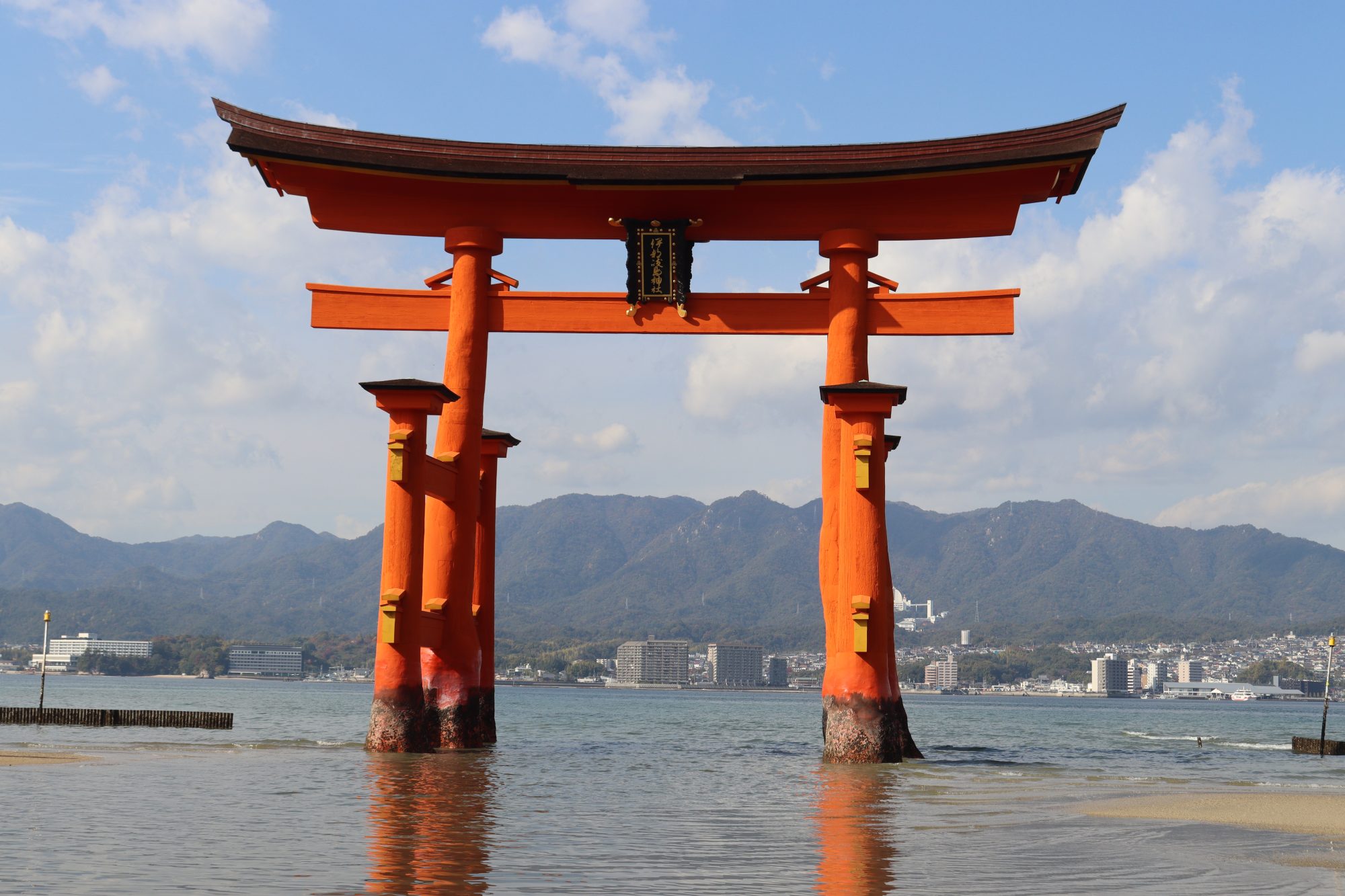 Portale torii rosso affacciato su un mare tranquillo con montagne sullo sfondo, Giappone