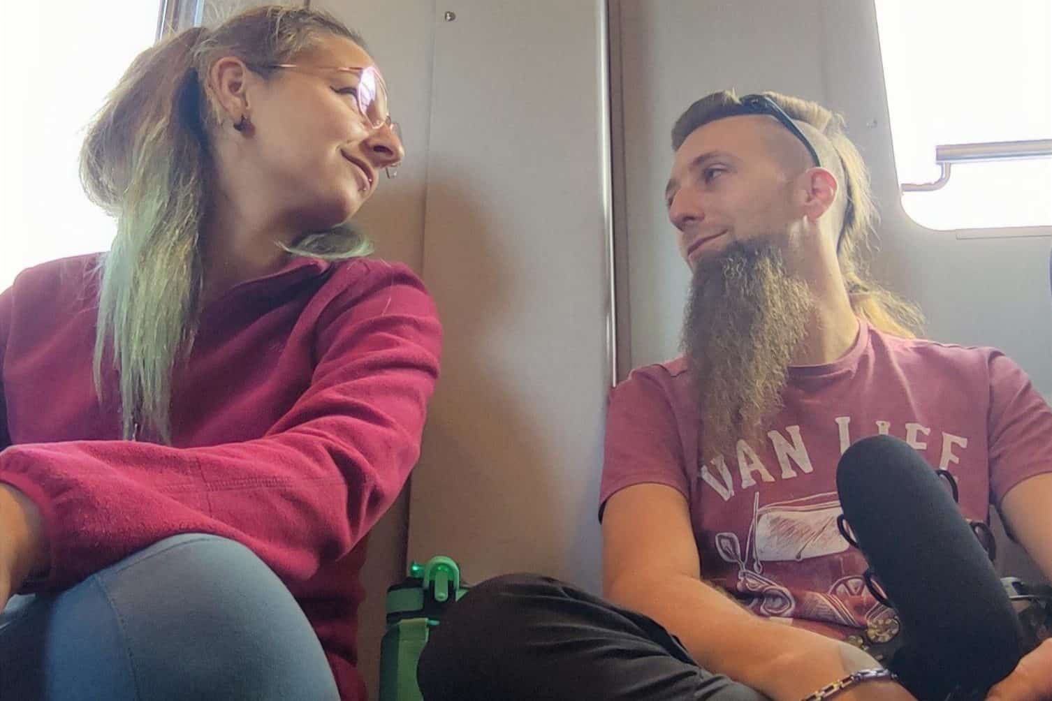 Due persone sedute su un mezzo pubblico, si scambiano sguardi affettuosi.