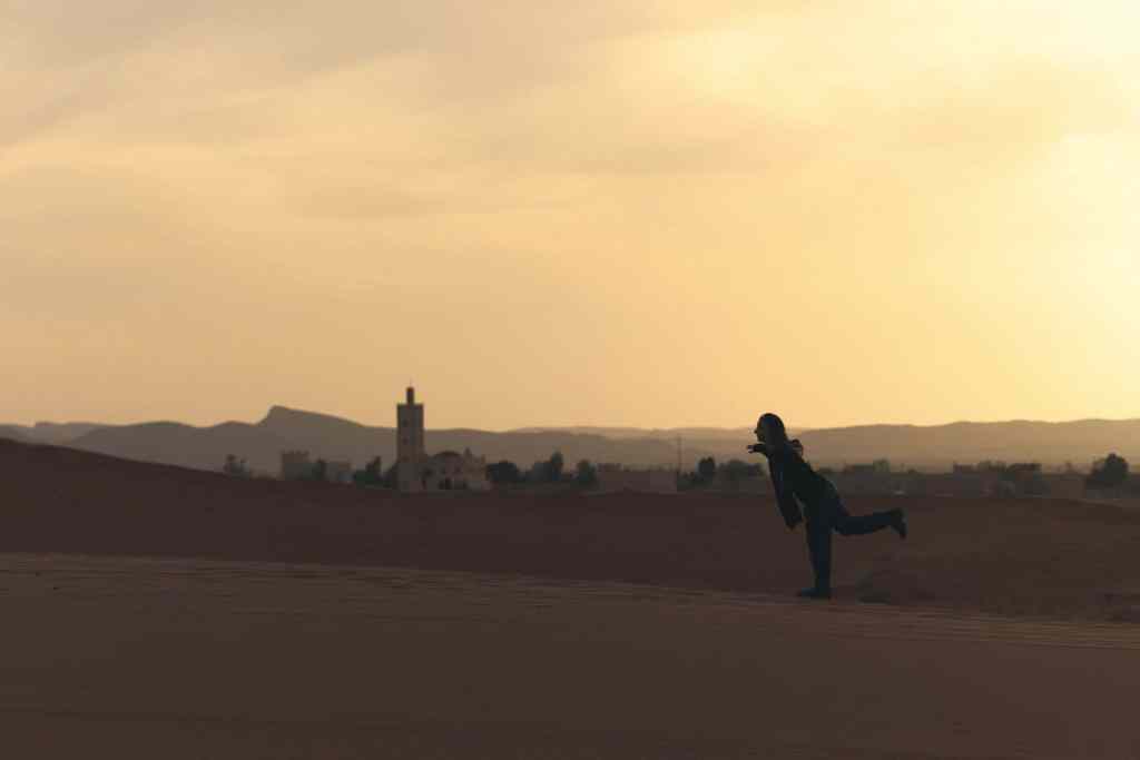 Eva in silhouette sulle dune del deserto in Marocco al tramonto